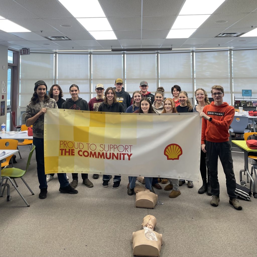 Students at a training session holding a Shell Canada banner with the text "Proud to Support the Community"